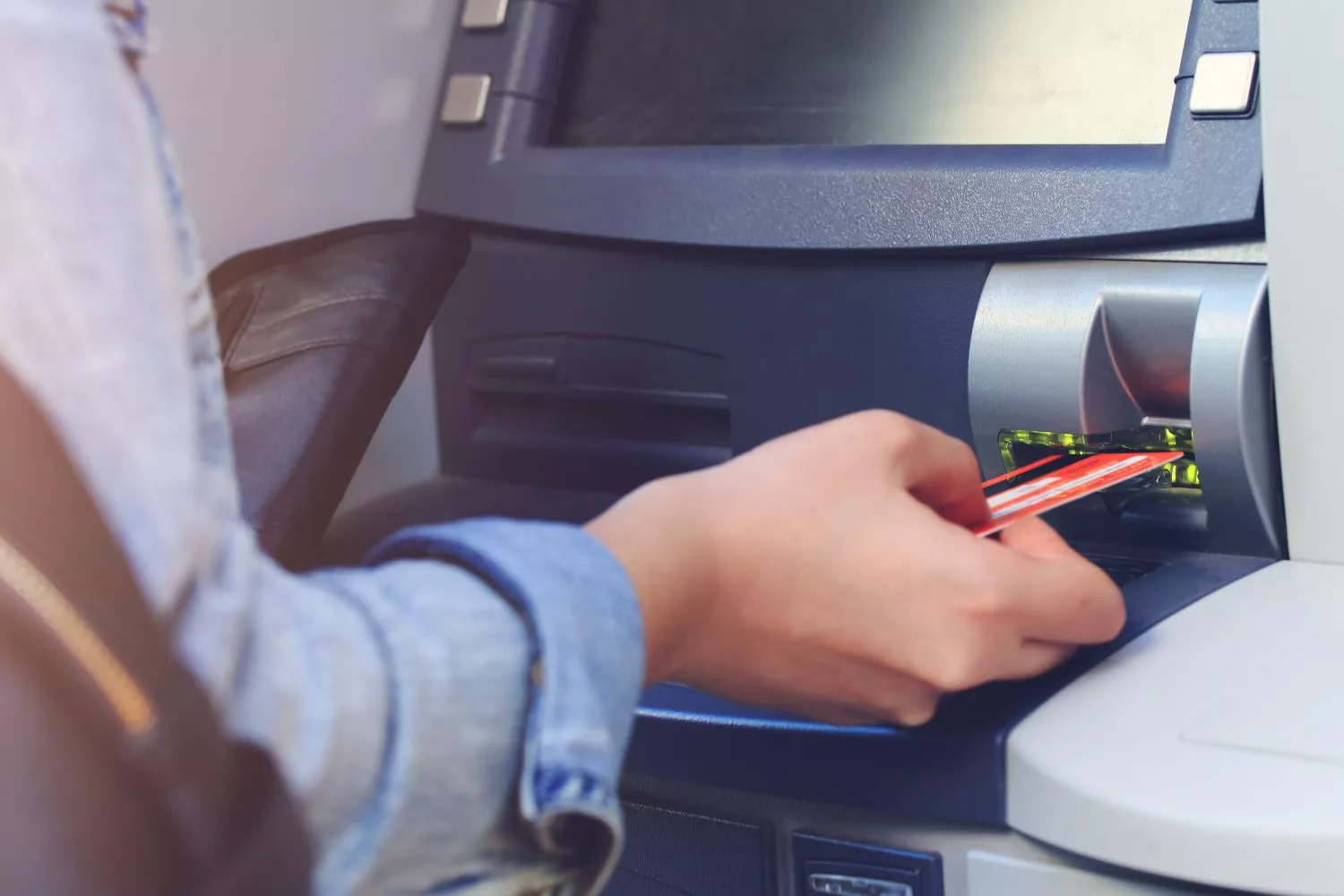 Una persona usa un cajero automático en la calle/ Montaje Consumidor Global