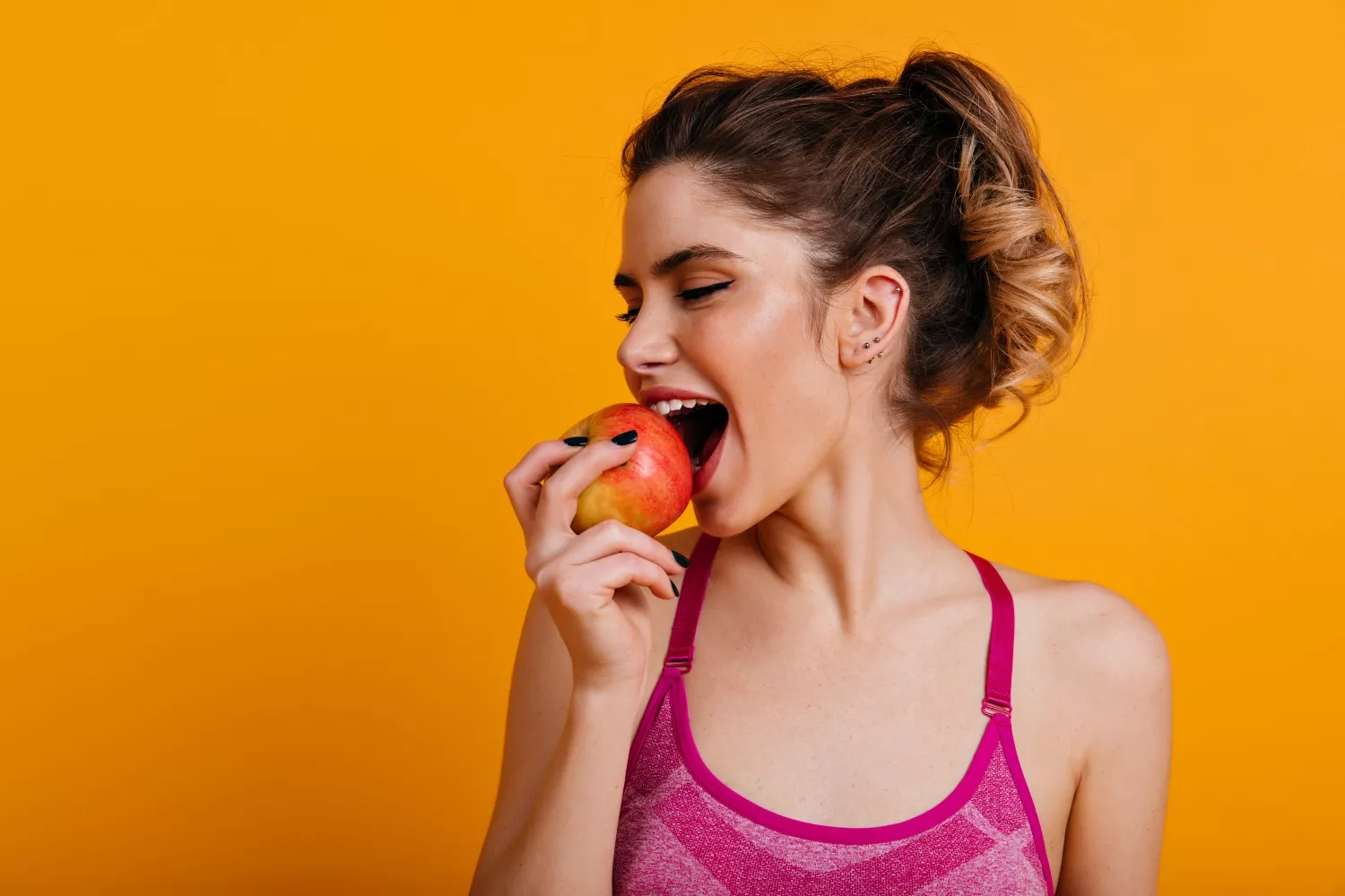 Una chica come una de las frutas que son saludables para la higiene bucal / FREEPIK