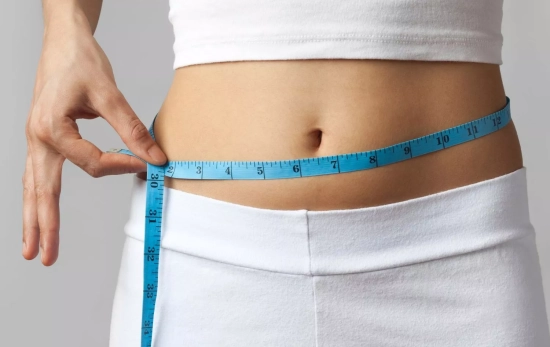 Una persona midiéndose el contorno de la cadera después de empezar a correr en invierno/ CANVA