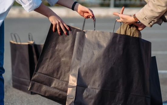 Dos personas con bolsas de ropa / FREEPIK - teksomolika