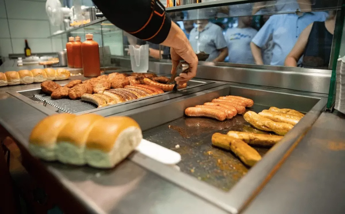 Un trabajador fríe salchichas en un restaurante de comida rápida / EFE