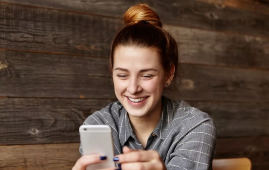 Una persona sonríe a su móvil / FREEPIK - wayhomestudio