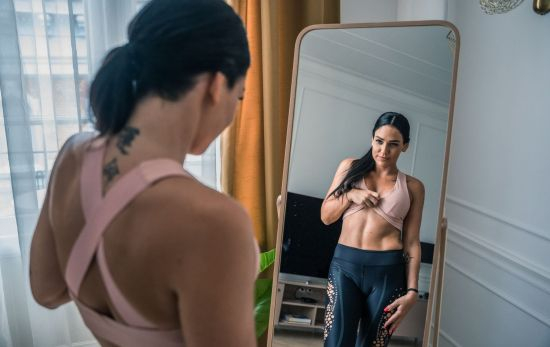 Una mujer observa sus abdominales en el espejo / Unsplash Una mujer observa sus abdominales en el espejo / Unsplash