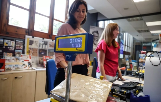 Una trabajadora pesa un paquete para enviar, en una oficina de Correos