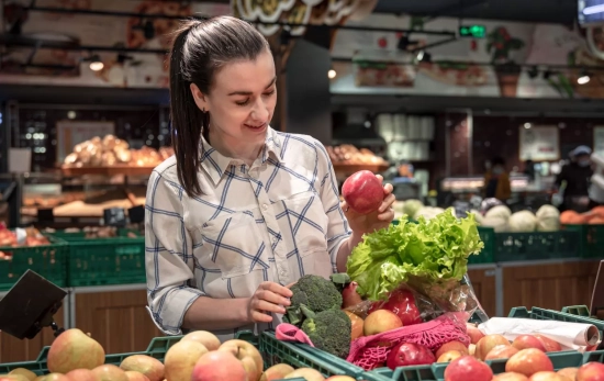 Una consumidora con frutas y verduras en el supermercado