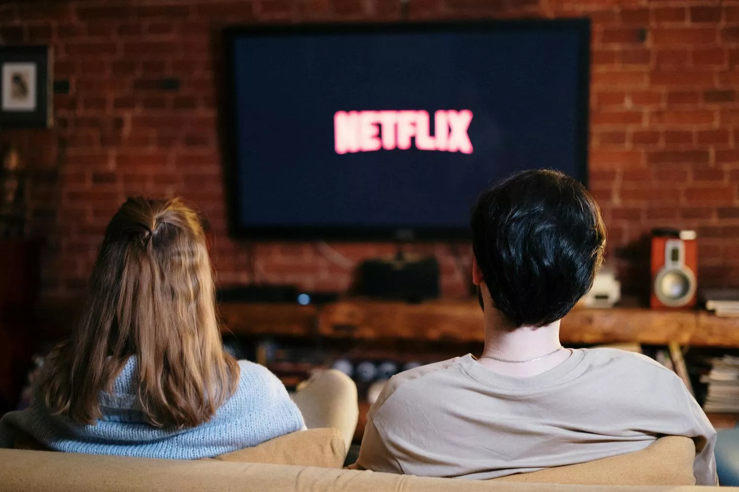 Pareja sentada en el sofá dispuesta a ver Netflix / PEXELS