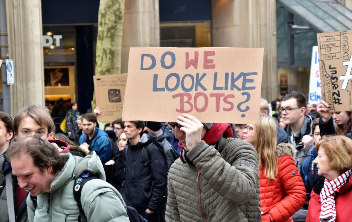 Un hombre muestra un cartel en una manifestación en el que se pregunta '¿Tenemos pinta de bots?' / Unsplash