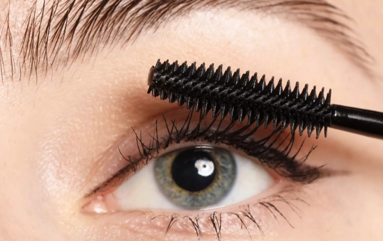 Una persona poniéndose máscara de pestañas/ CANVA