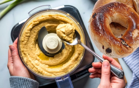Una persona rellena un bagel de hummus/ Montaje Consumidor Global