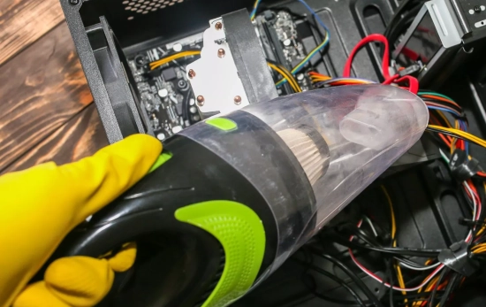 Una persona aspirando por dentro la batería del ordenador/ CANVA