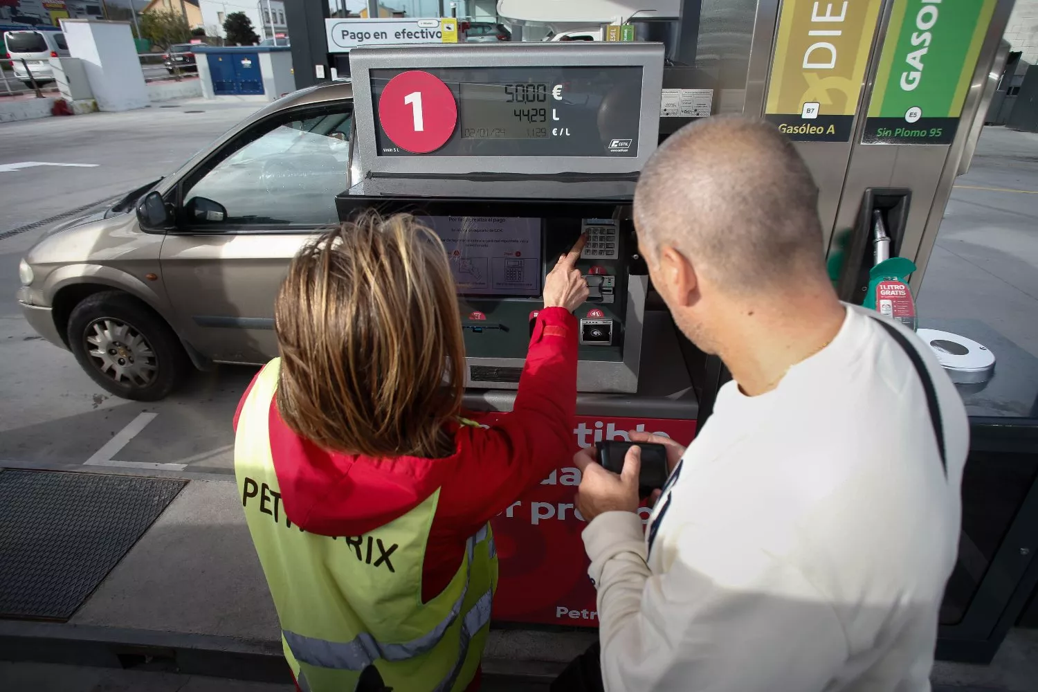 Una trabajadora ayuda a un hombre a repostar combustible en una gasolinera / EUROPA PRESS - CARLOS CASTRO
