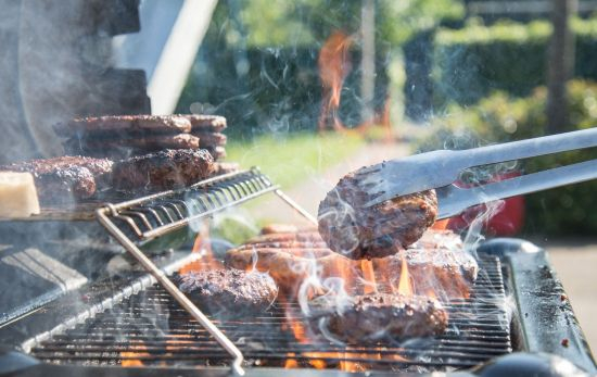 Una persona prepara hamburguesas en una barbacoa / UNSPLASH