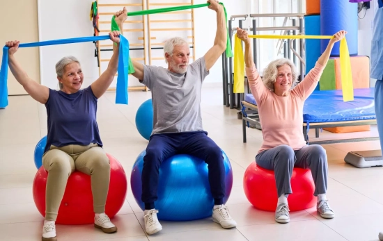 Tres personas de edad avanzada ejercitando la fuerza de sus brazos/ CANVA