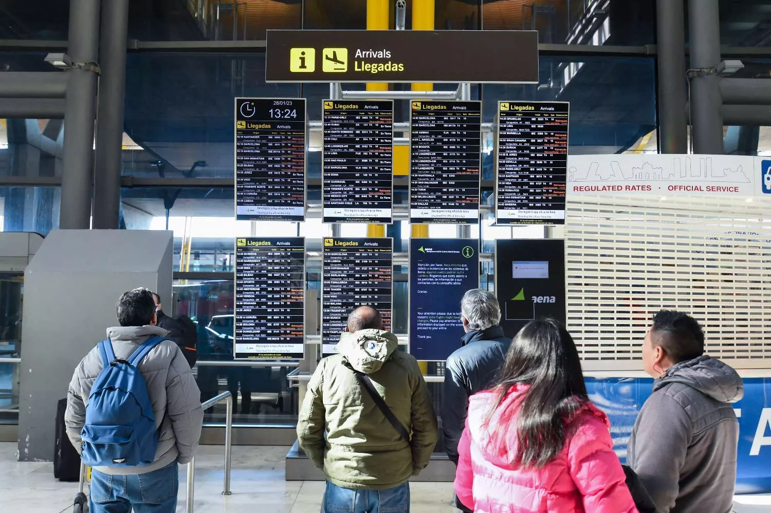 Varias personas observan los paneles informativos que anuncian retrasos de llegadas en algunos vuelo