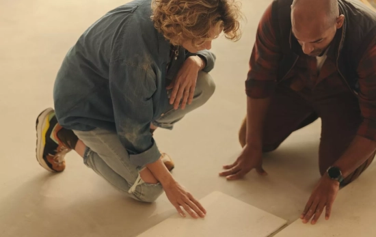 Dos personas colocando las baldosas autoadhesivas como las del Action/ CANVA