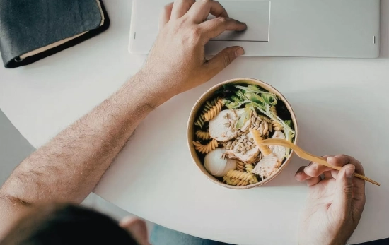 Una persona comiendo frente al ordenador/ CANVA
