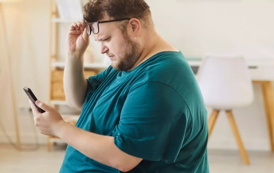 Una persona sedentaria mira el móvil en su descanso de trabajo/ CANVA