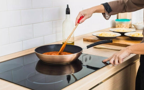 Una persona cocina y enciende su vitrocerámica / FREEPIK