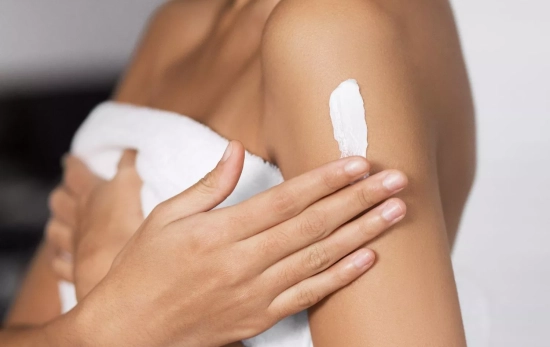 Una mujer aplicándose la crema de Mercadona/ CANVA