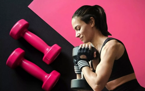 Una mujer entrenando brazos/ CANVA