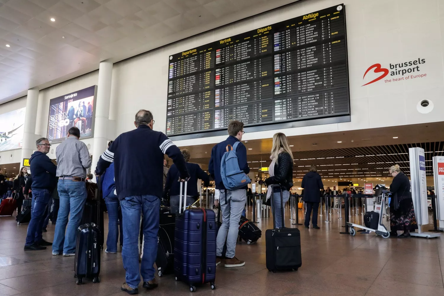 Viajeros consultan una pantalla que muestra vuelos cancelados en el aeropuerto de Bruselas / Thierry Roge - EP