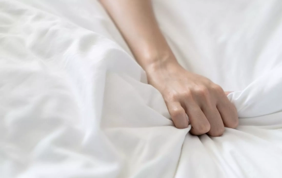 Una mano de una persona agarrando una sábana/ CANVA Una mano de una persona agarrando una sábana/ CANVA
