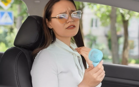 Una mujer pasando calor en el coche/ CANVA