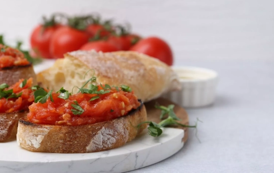 Pan con tomate en la mesa/ CANVA Pan con tomate en la mesa/ CANVA