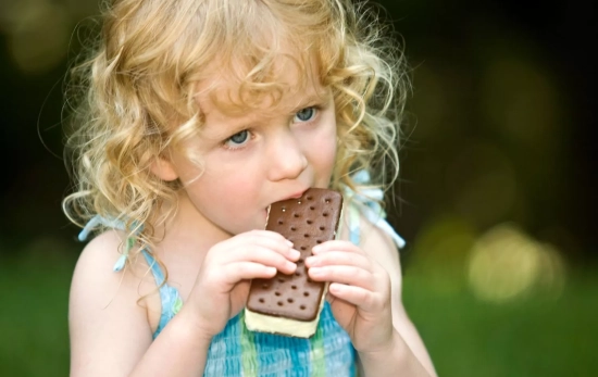 Una niña comiendo un sándwich de nata/ CANVA Una niña comiendo un sándwich de nata/ CANVA