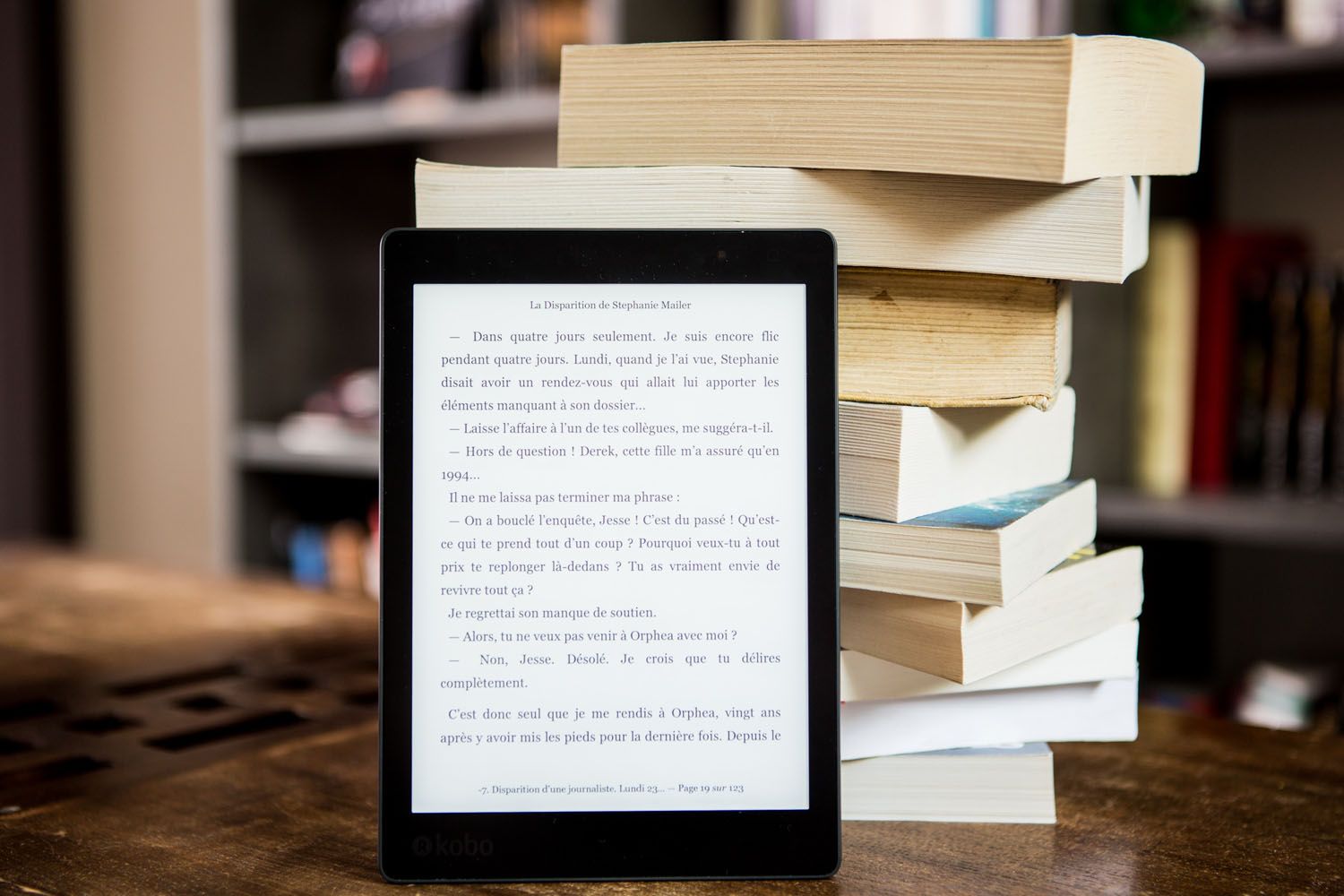 Un libro digital y libros en papel sobre una mesa / PEXELS