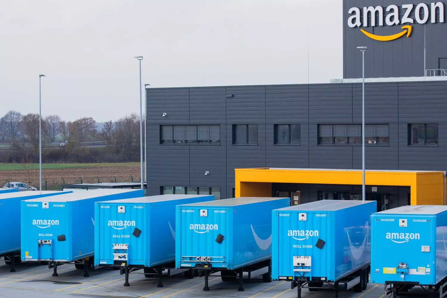 Camiones con el logotipo de Amazon se encuentran frente a un centro logístico de la empresa   Rolf V