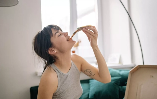 Una persona disfruta una pizza / PEXELS