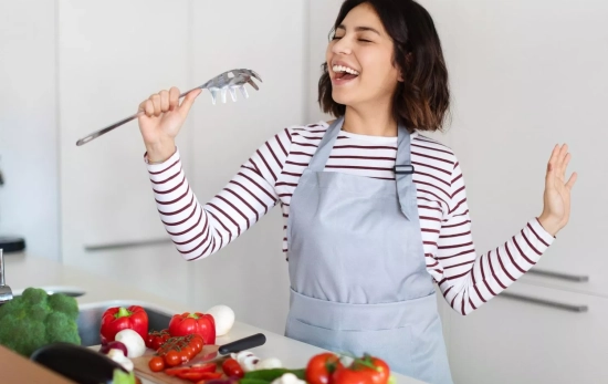 Una persona cocinando mientras canta/ CANVA Una persona cocinando mientras canta/ CANVA