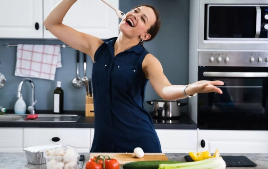 Una mujer cantando canciones mientras cocina/ CANVA Una mujer cantando canciones mientras cocina/ CANVA