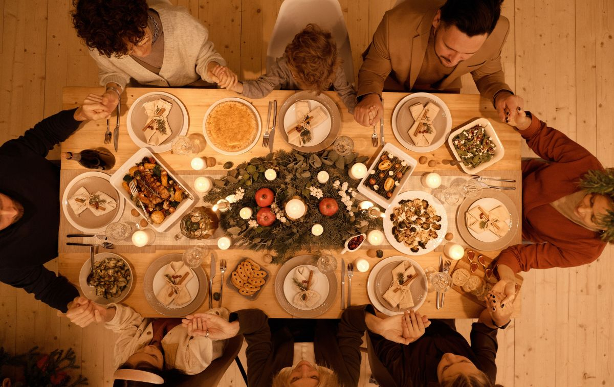 Una familia se reúne en torno a una mesa llena de alimentos por Navidad / PEXELS
