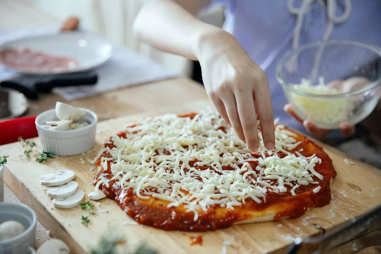 Una persona prepara una pizza   PEXELS