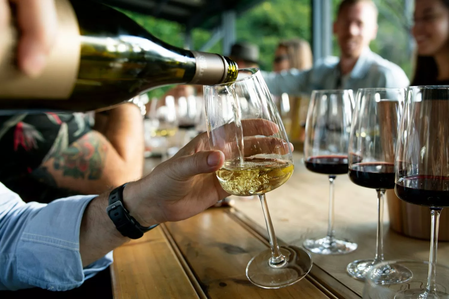 Una persona sirve una copa de vino blanco   UNSPLASH