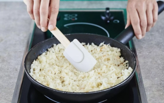 Una persona salteando migas de coliflor/ CANVA