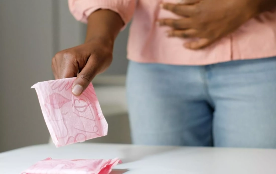 Una mujer cogiendo una compresa en sus días de regla/ CANVA