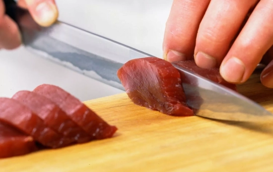 Una persona cortando atún crudo/ CANVA Una persona cortando atún crudo/ CANVA