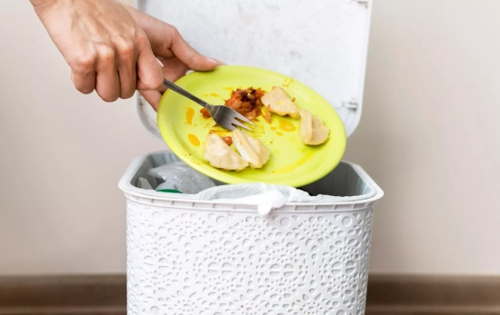 Una persona tira comida a la basura / MAGNIFIC