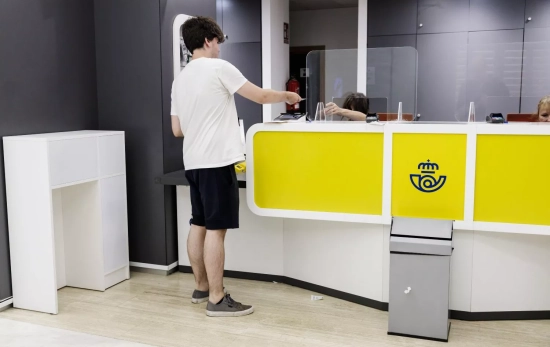 Un joven es atendido en la oficina de Correos / EUROPA PRESS - CARLOS LUJÁN