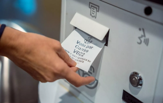Una persona recoge el ticket para solicitar el voto por correo
