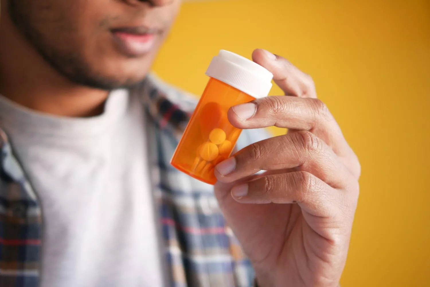 Una persona sostiene un bote con pastillas   PEXELS