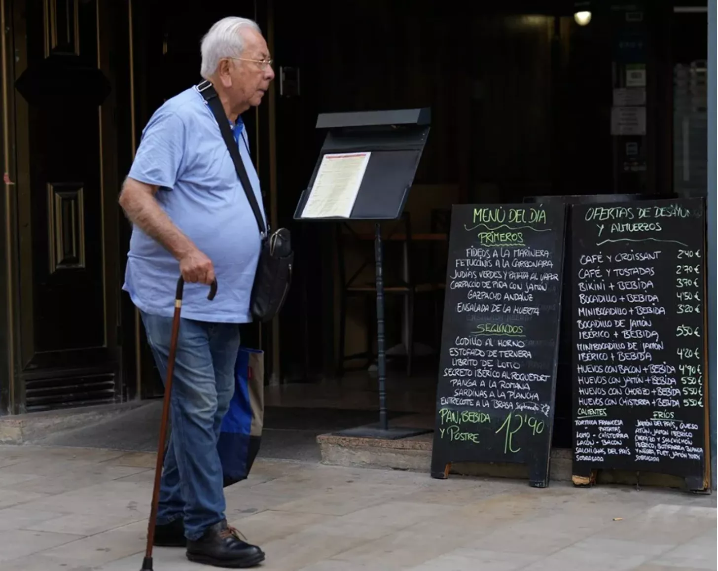 Un señor pasa ante las pizarras del menú de un restaurante / EFE - Alejandro García