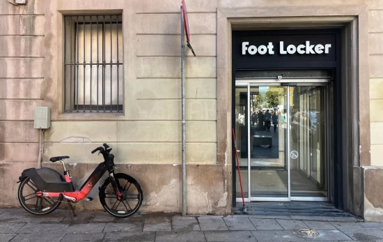 Una bicicleta quemada y astillas junto a la puerta de Foot Locker en Barcelona / TC