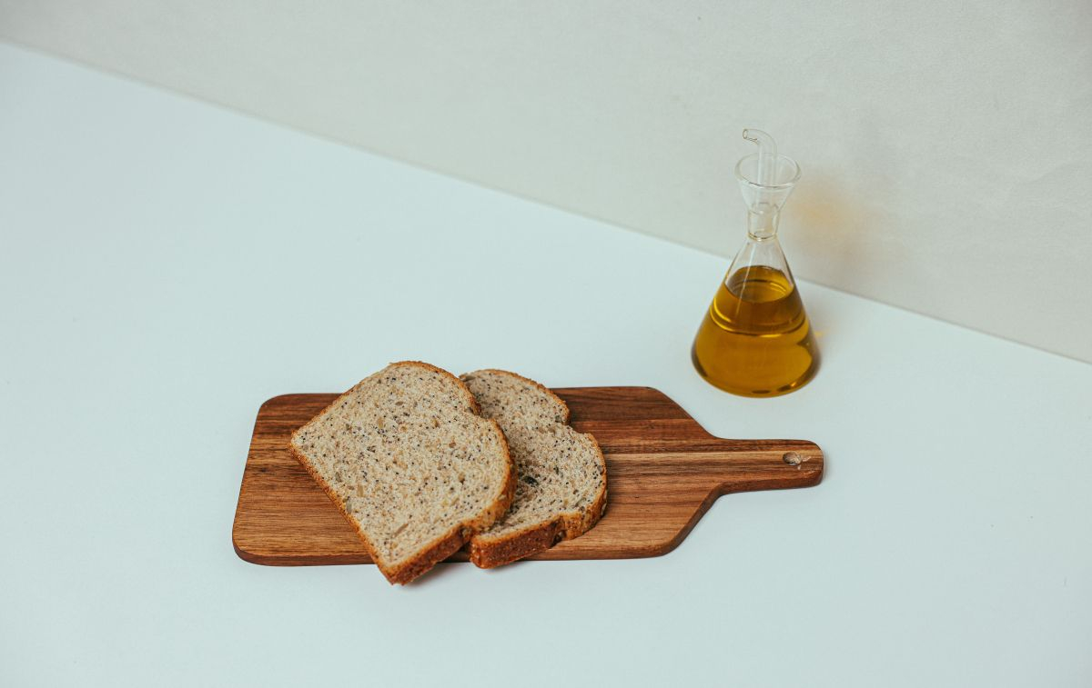 Una garrafa de aceite de oliva junto a un par de tostadas / PEXELS