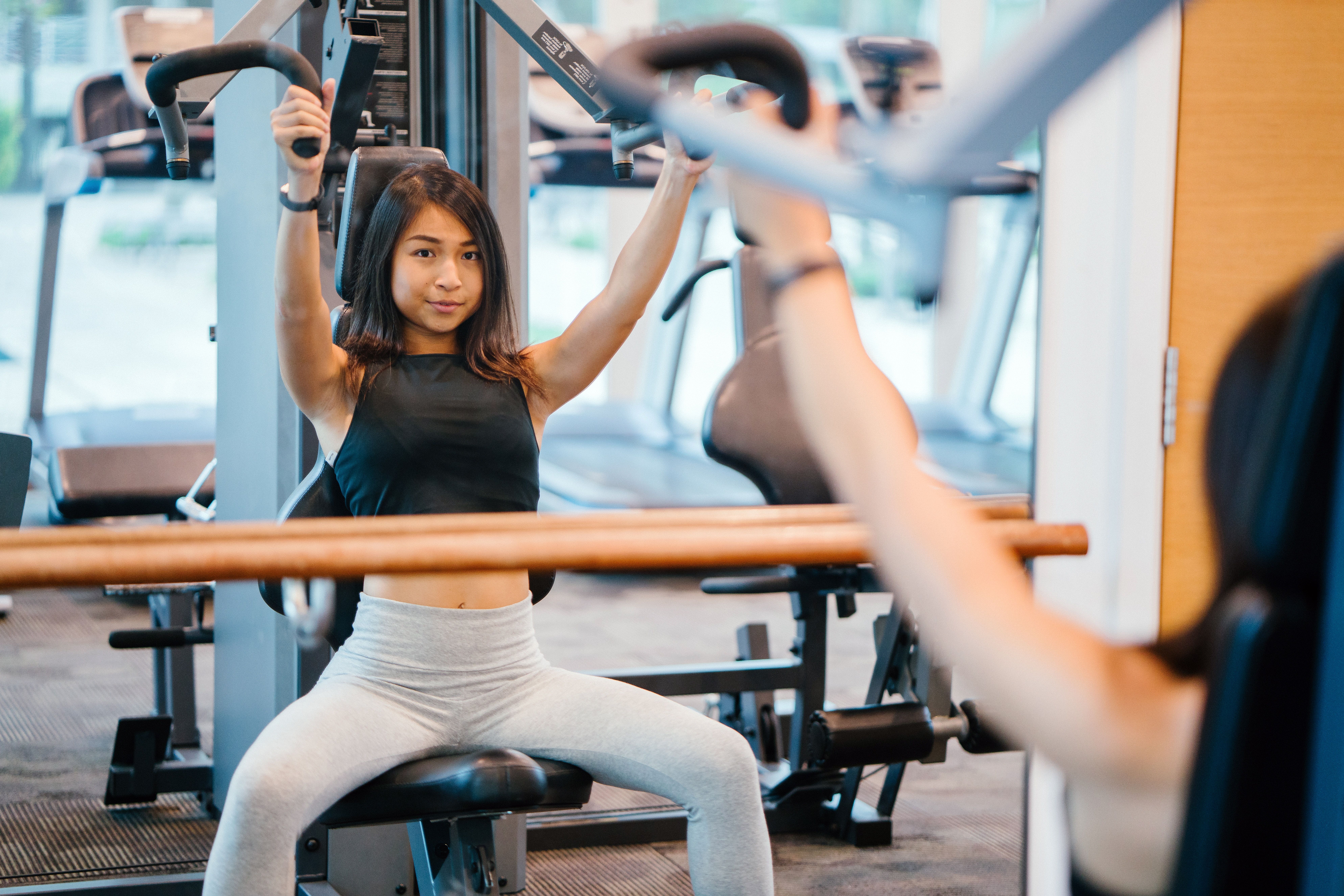 Una mujer hace ejercicios de pecho en una máquina del gimnasio / PEXELS