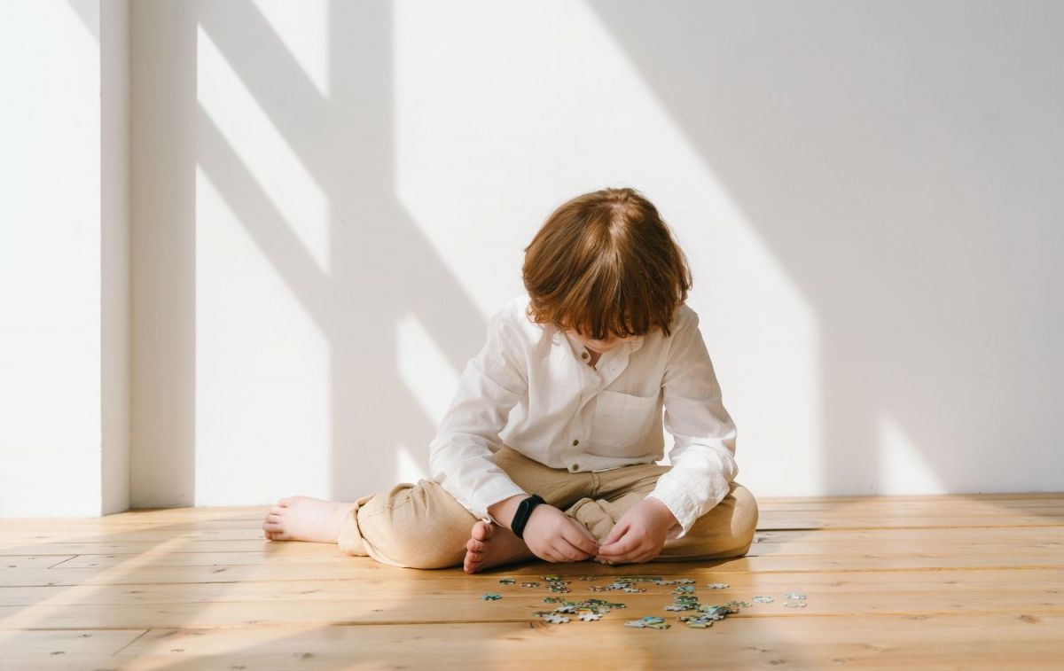 Un niño juega en el suelo con un puzzle / PEXELS
