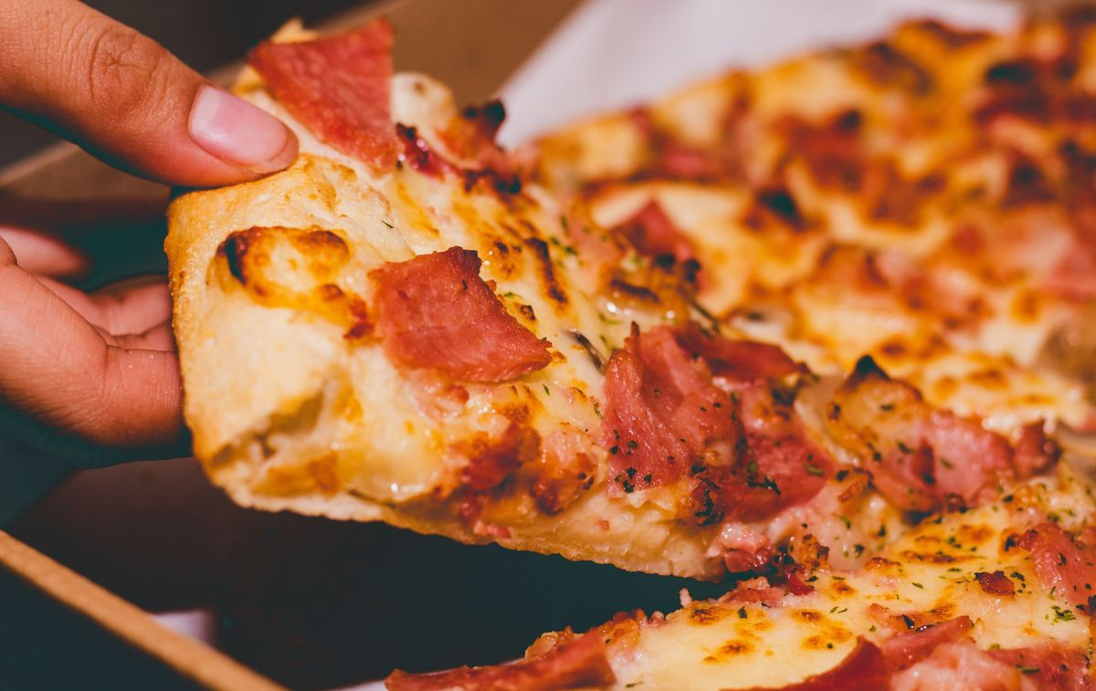 Un usuario coge una porción de pizza de Telepizza / PEXELS
